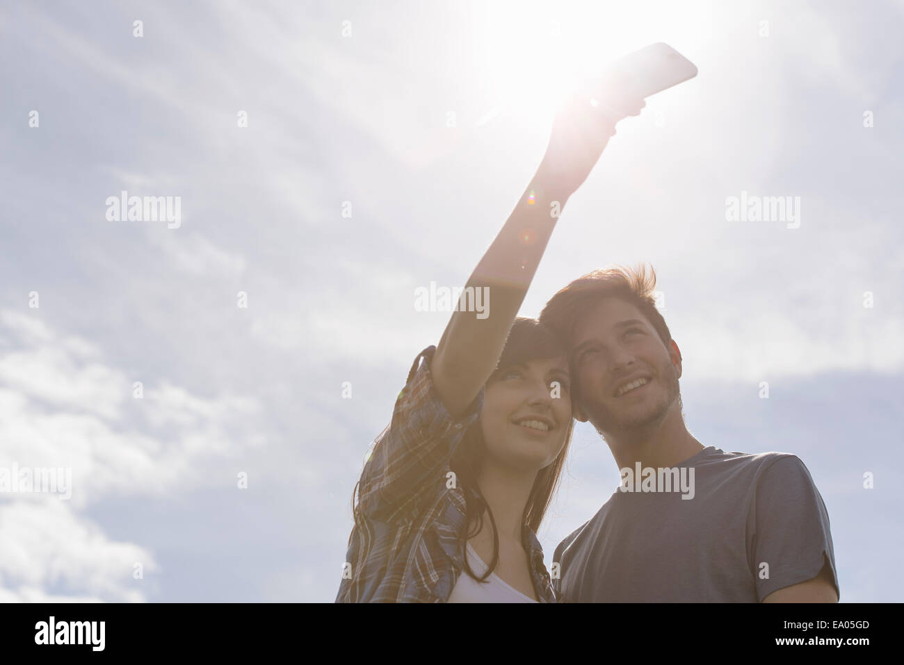 Junges Paar unter Selbstportrait auf Handy unter strahlend sonnigen Himmel Stockfoto