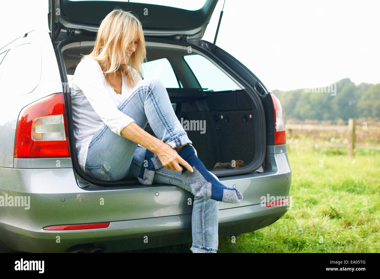 Frau sitzt am Heck des Autos Socken anziehen Stockfoto