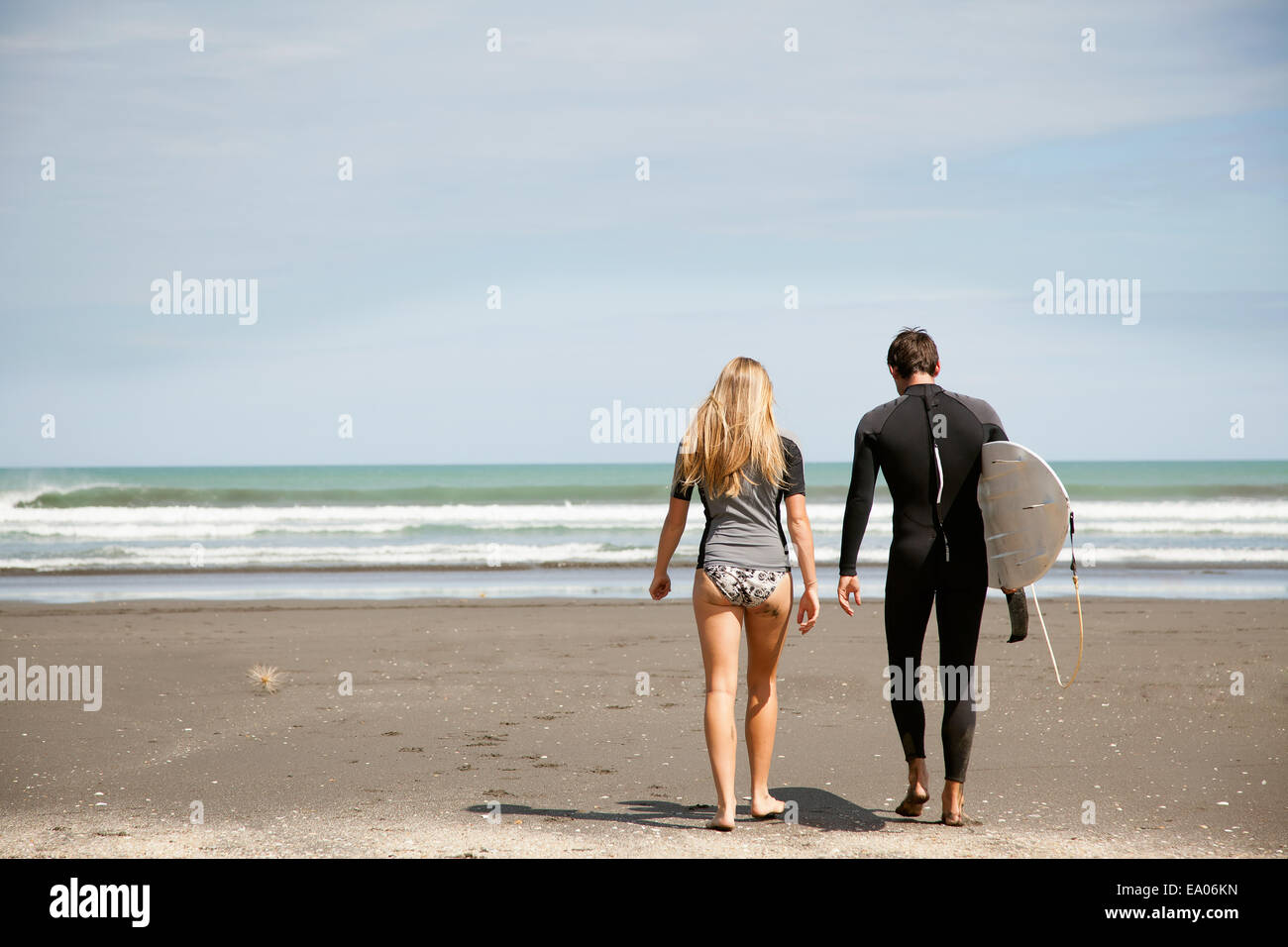 Junges Paar zu Fuß aus Meer, Mann Junge tragenden Surfbrett Stockfoto