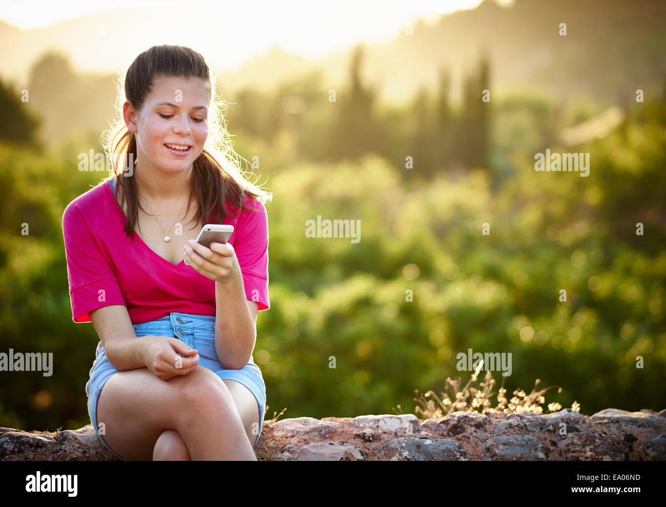 Teenager-Mädchen sitzen auf Steinmauer Blick auf Smartphone, Mallorca, Spanien Stockfoto