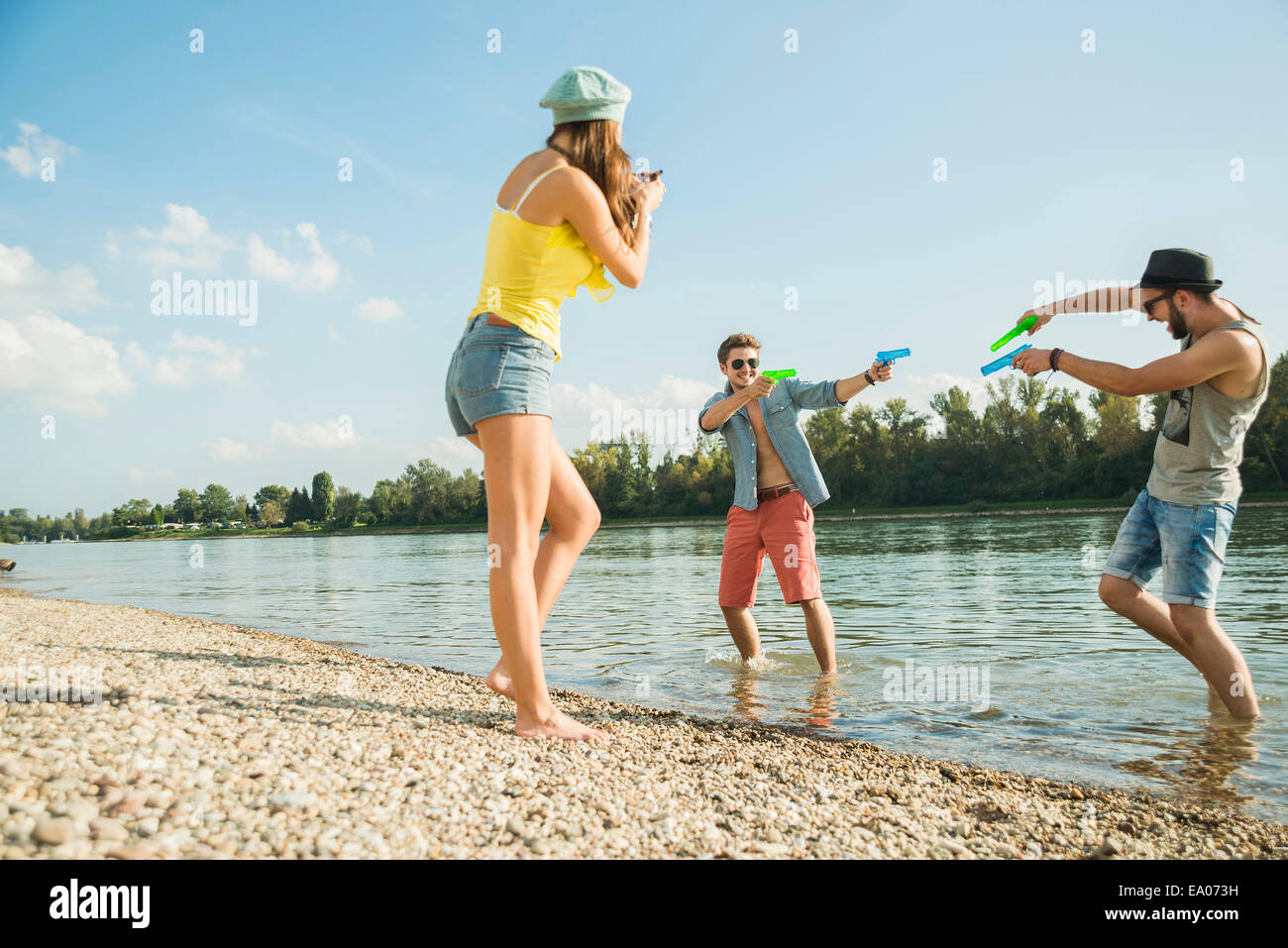 Junge Männer spielen mit Wasserpistolen in See Stockfoto