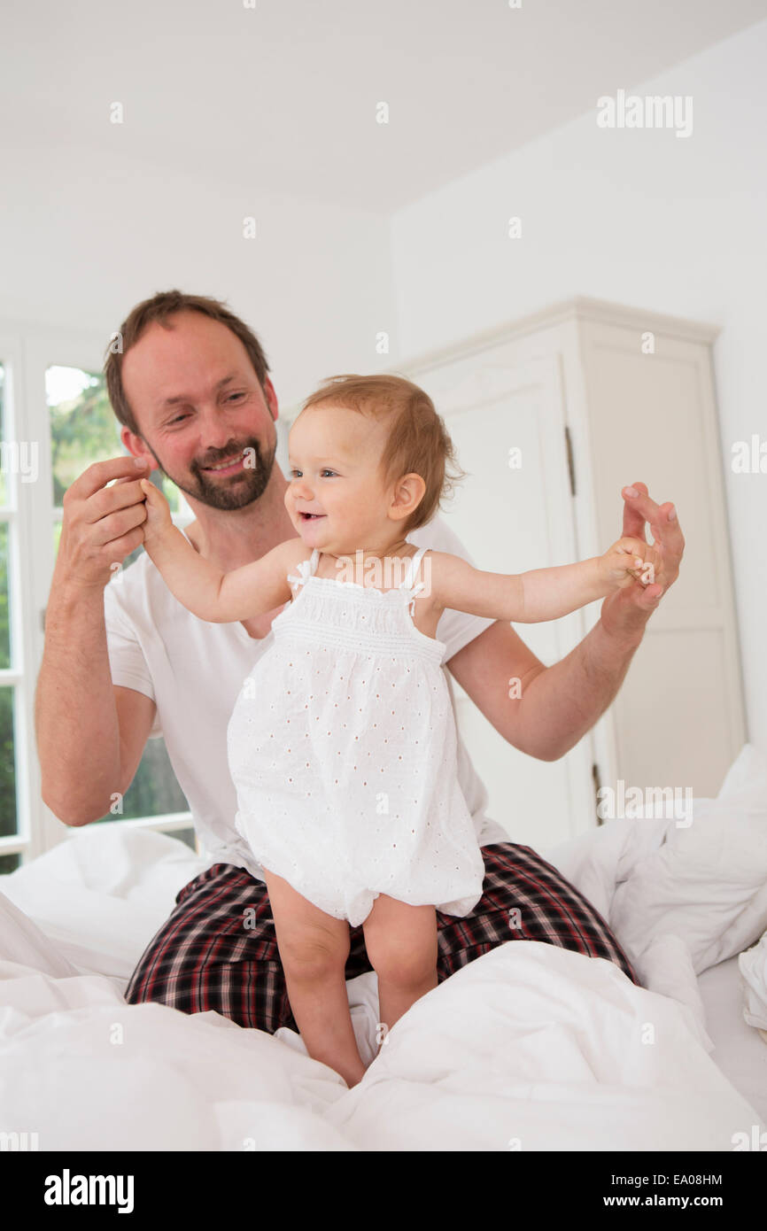 Vater mit Tochter auf Bett spielen Stockfoto