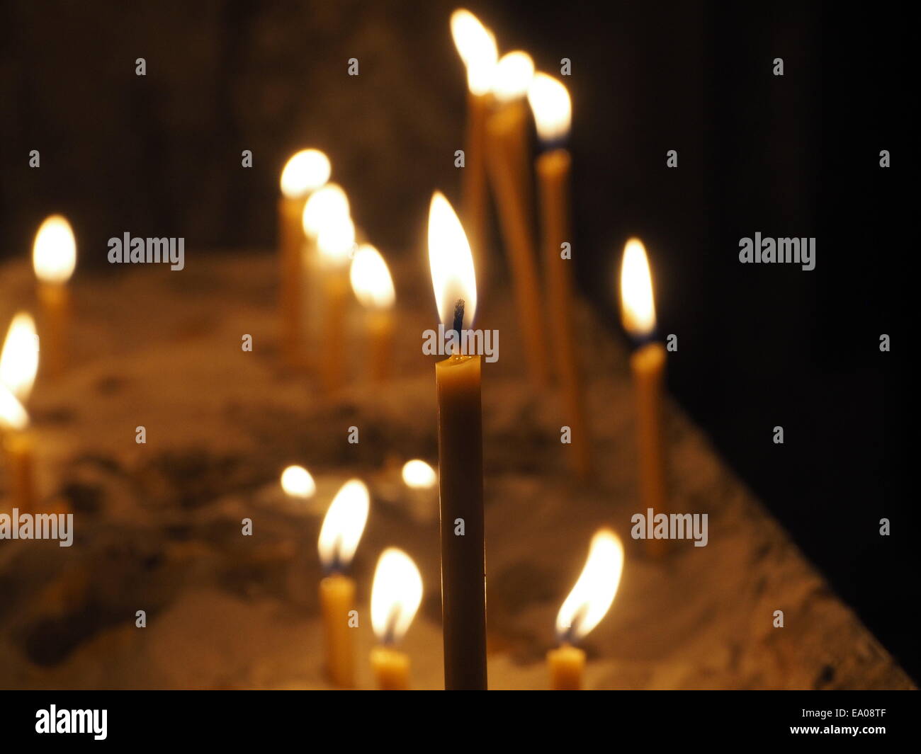 Votive-Kerzen flackern in der Dunkelheit einen Kirchenraum Gießen weiches diffuses Licht Stockfoto