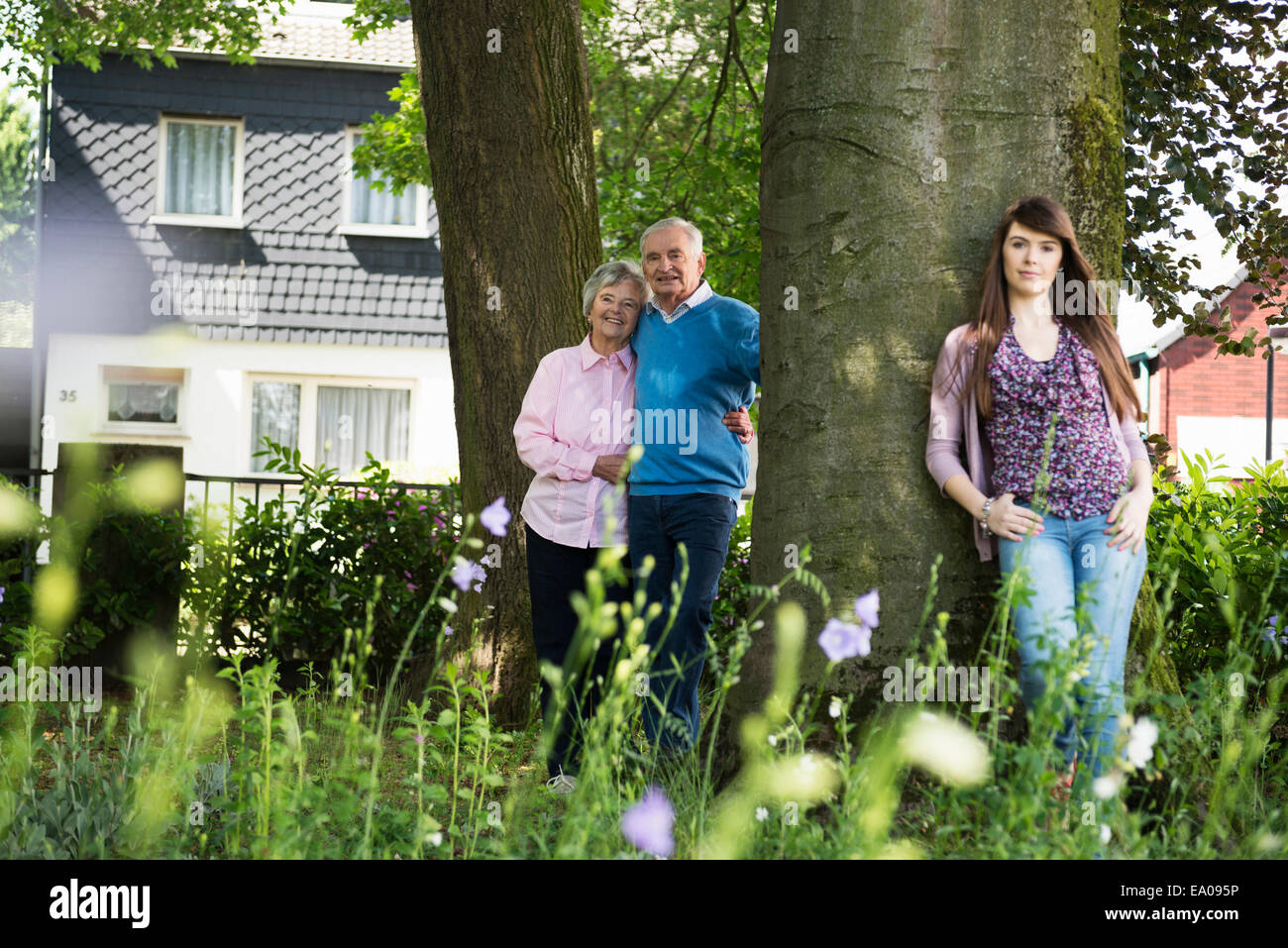 Großeltern und Enkeltochter von Baum stehend Stockfoto