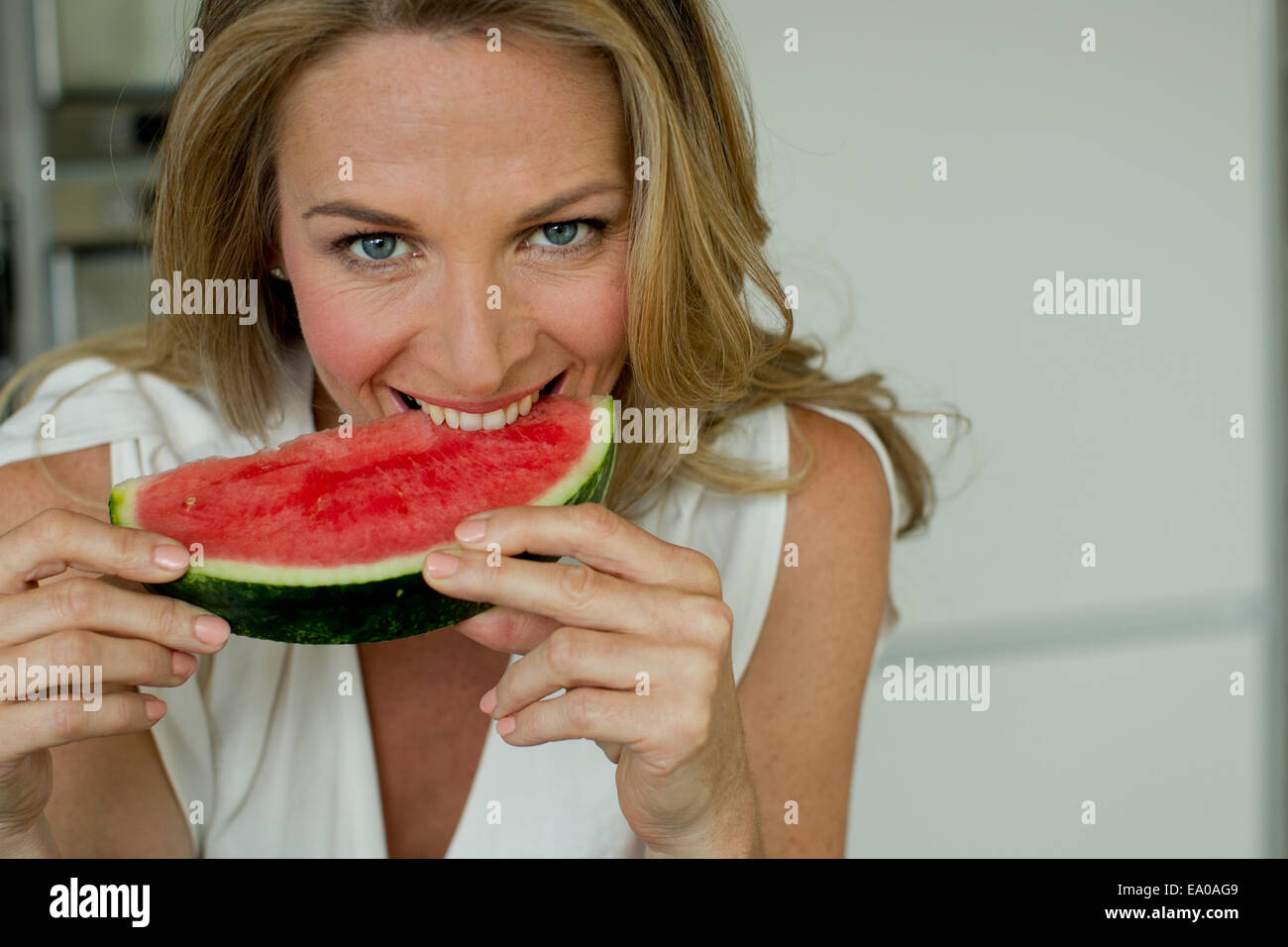 Reife Frau beißen Wassermelone Stockfoto