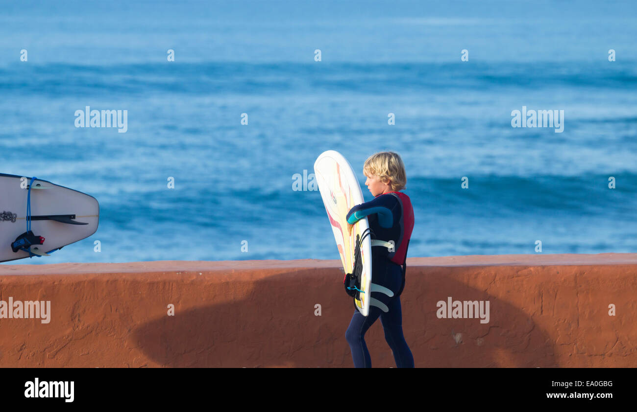 Junge blonde Surfer mit Surfbrett. Stockfoto