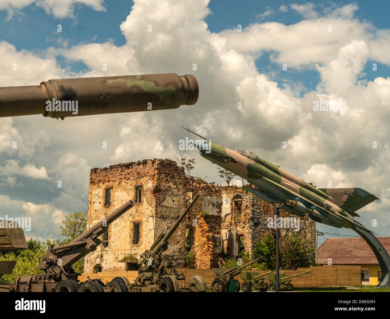 Kombination Image Tank Gewehrlauf, Düsenjäger und Feld-Kanonen, mit verfallenen Gebäude im Hintergrund. Stockfoto