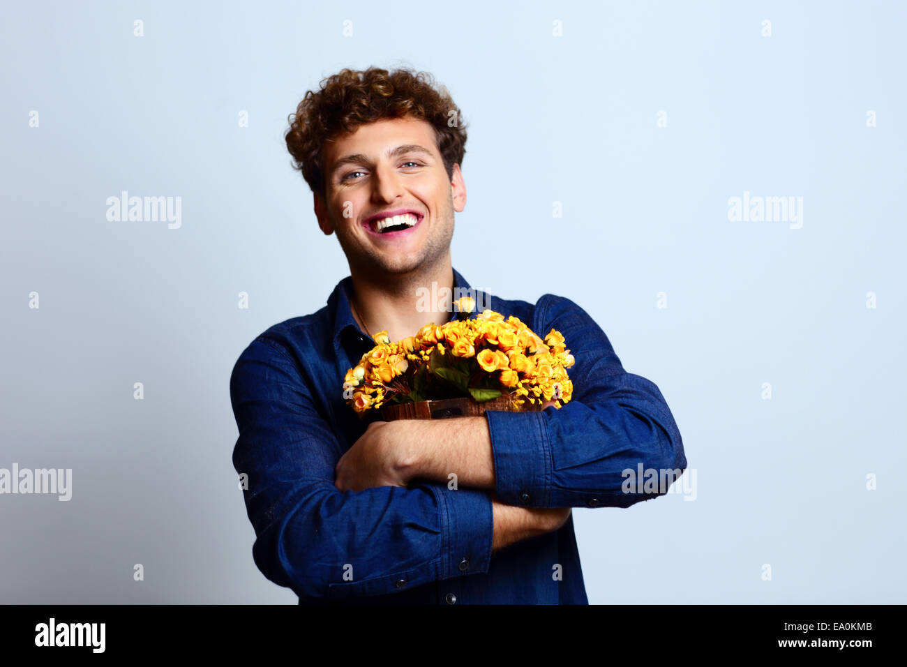 Glücklicher Mann umarmt Eimer mit Blumen Stockfoto