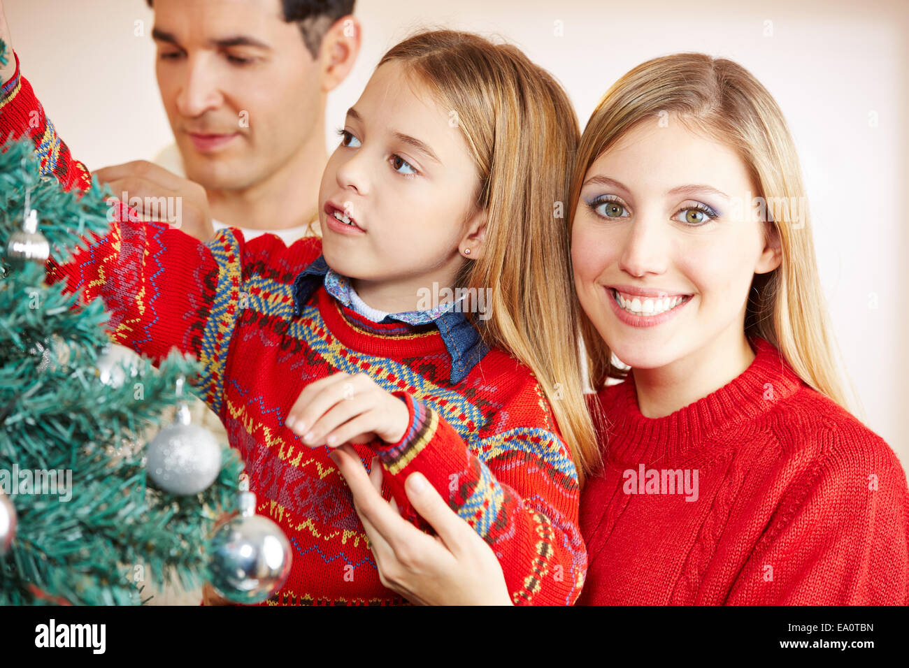 Eltern schmücken Weihnachtsbaum zusammen mit ihrer Tochter Stockfoto