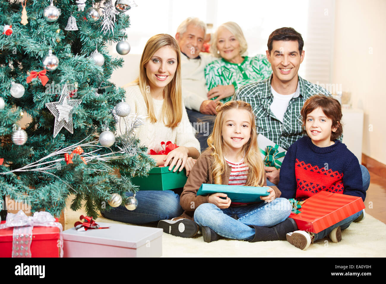 Familie Weihnachten zu feiern, mit drei Generationen unter Baum mit Geschenken Stockfoto