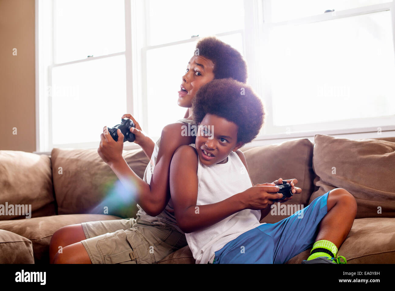 Zwei Brüder Rücken an Rücken beim game-Controller im Wohnzimmer spielen Stockfoto