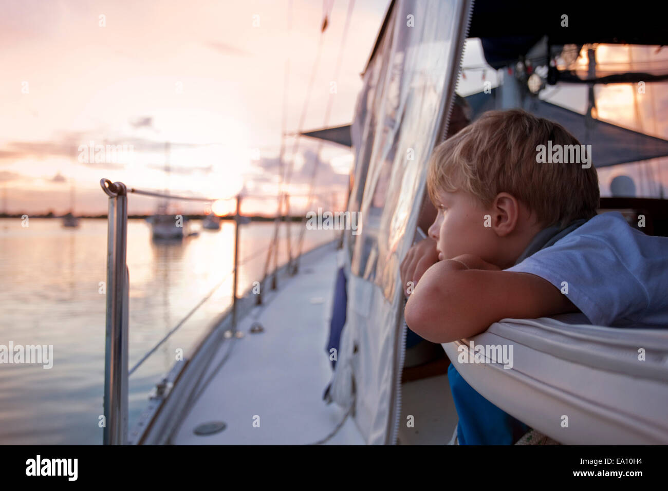 Junge blicken hinaus auf das Meer vom Segelboot bei Sonnenuntergang Stockfoto