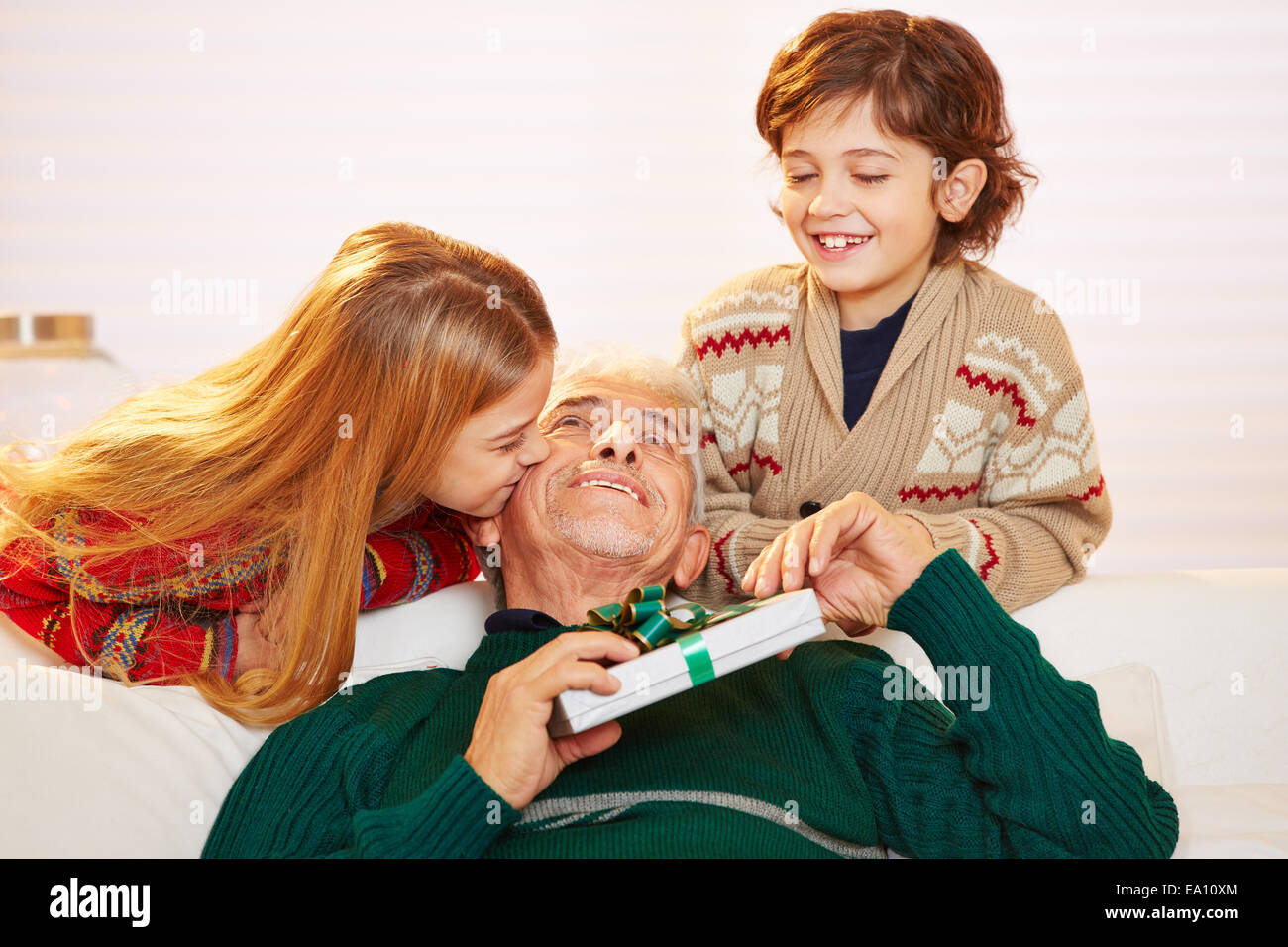 Mädchen küssen Großvater mit Geschenk auf die Wange zu Weihnachten Stockfoto