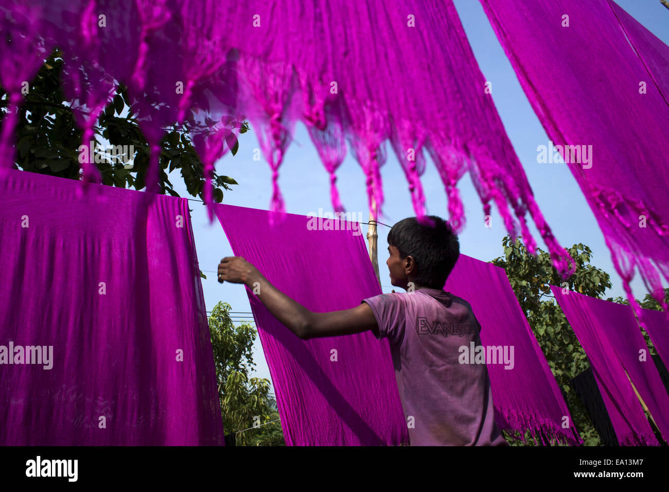 Narayangonj, Bangladesch. 5. November 2014. Ein Junge gefärbte Tücher unter Sonne trocknen, hilft er Familienunternehmen. Dorfbewohner in Bangladesch Hand gefärbte Kleidung Geschäfte zu machen. Kleinkredit nehmen sie sammeln, roh Tücher aus Fabrik, nachdem gefärbt sie unter Sonne getrocknet und dann verkaufen sie im Markt und sie sind jetzt stabil. © Zakir Hossain Chowdhury/ZUMA Draht/Alamy Live-Nachrichten Stockfoto