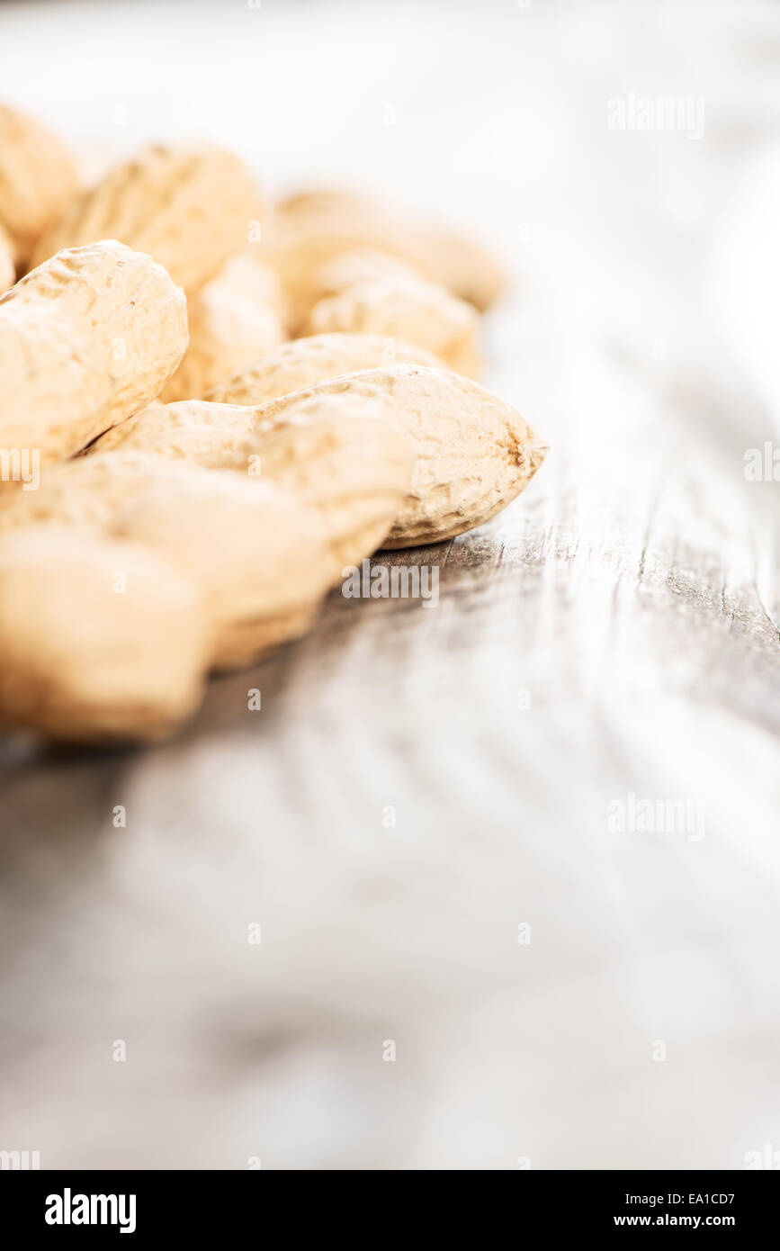 Erdnüsse in der Schale am Holztisch high-key Stockfoto