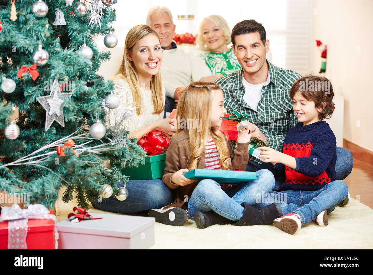 Glückliche Familie mit Großeltern machen Geschenke am Weihnachtsabend Stockfoto
