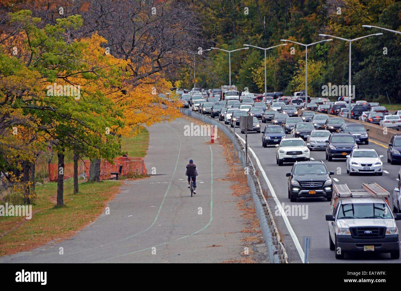 Ein Mann, Radfahren in der Nähe von Kfz-Verkehr an einem Herbsttag in der Nähe der Marina in Bayside, Queens, New York Stockfoto