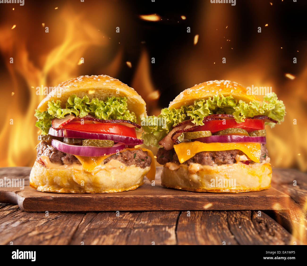 Frische hausgemachte Hamburger serviert auf Holzbohlen. Feuer Flammen um Stockfoto