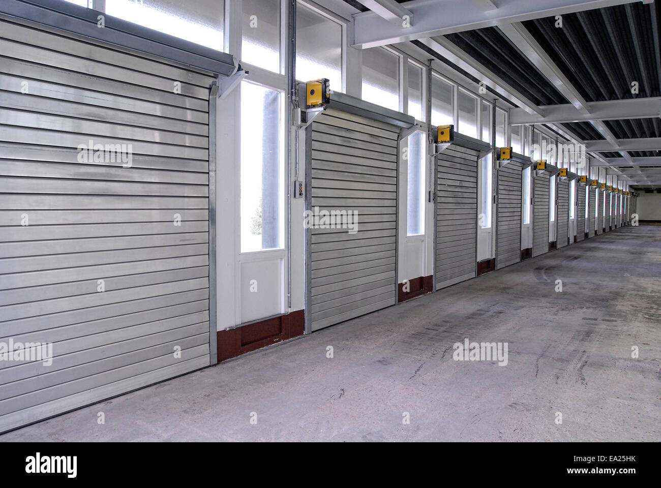 Eine lange Reihe von geschlossenen Rolltoren in einer Lagerhalle Stockfoto