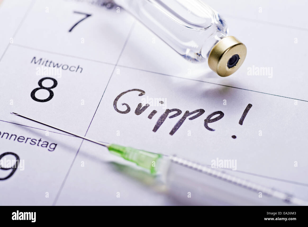 Spritze und Impfstoff in einem Kalender mit dem Datum für die Influenza-Impfung. Stockfoto