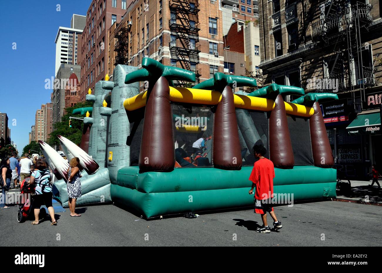 NYC: Fantasievolle Kunststoff aufgeblasenen Spielhaus von Palmen gesäumt bietet Spiel und Spaß für Kinder beim Straßenfest Stockfoto