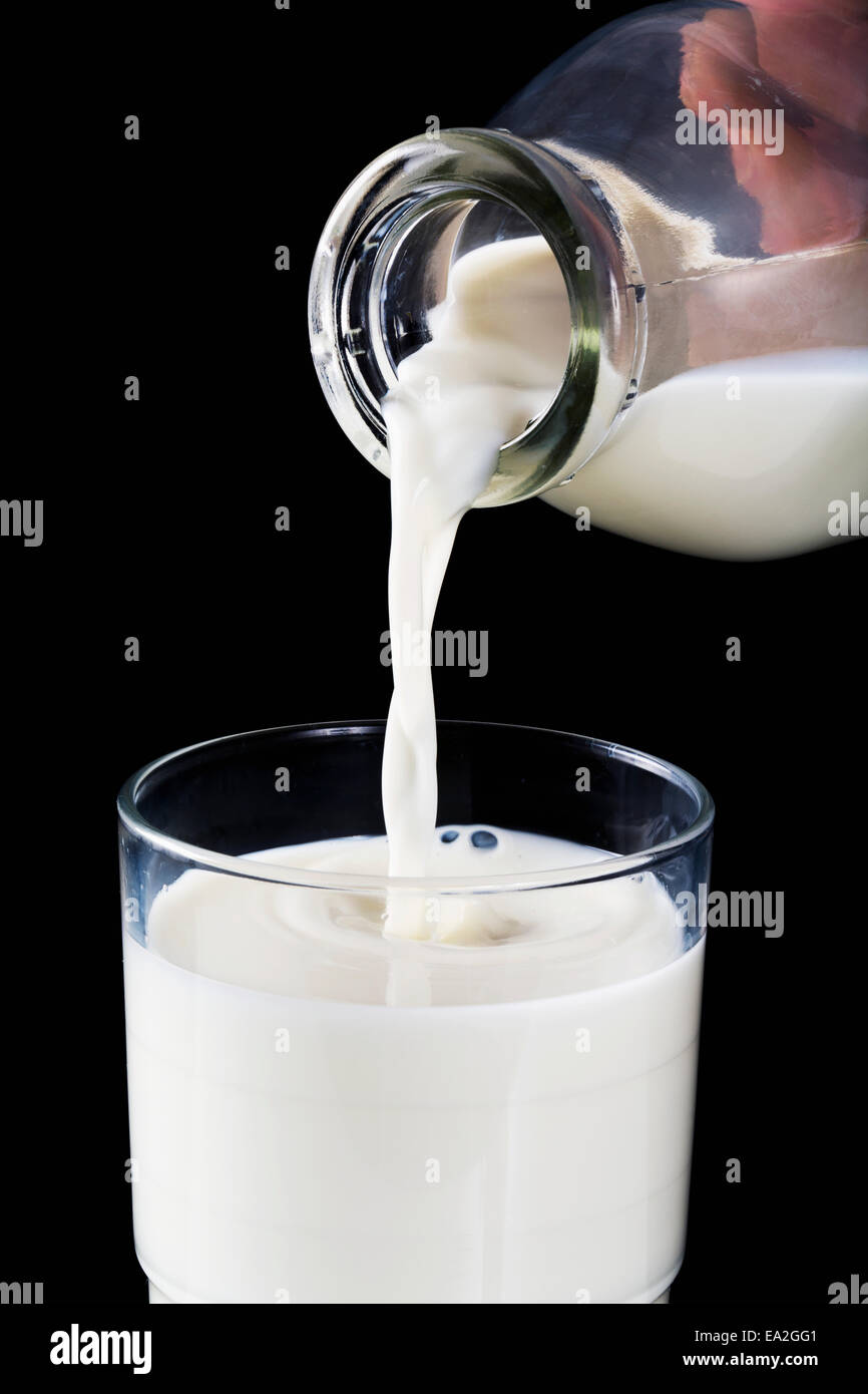 Glasflasche Milch in Glas mit schwarzem Hintergrund; Calgary, Alberta, Kanada Stockfoto