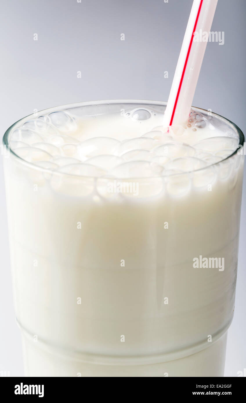 Glas Milch mit Bläschen und rot gestreift Stroh auf weißem Hintergrund; Calgary, Alberta, Kanada Stockfoto