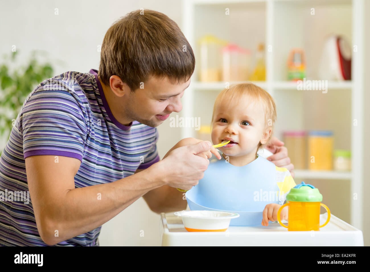 junger Vater lehrt seinen Sohn mit Löffel zu essen Stockfoto