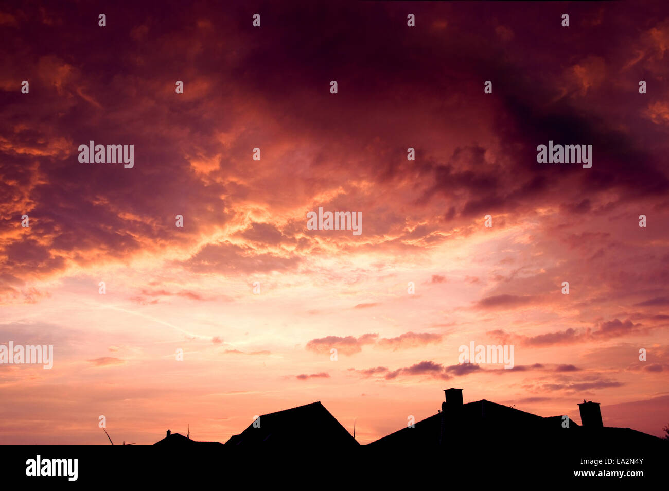 Sonnenuntergang Roter Himmel mit dunklen dramatische Wolken über Häuser. Stockfoto