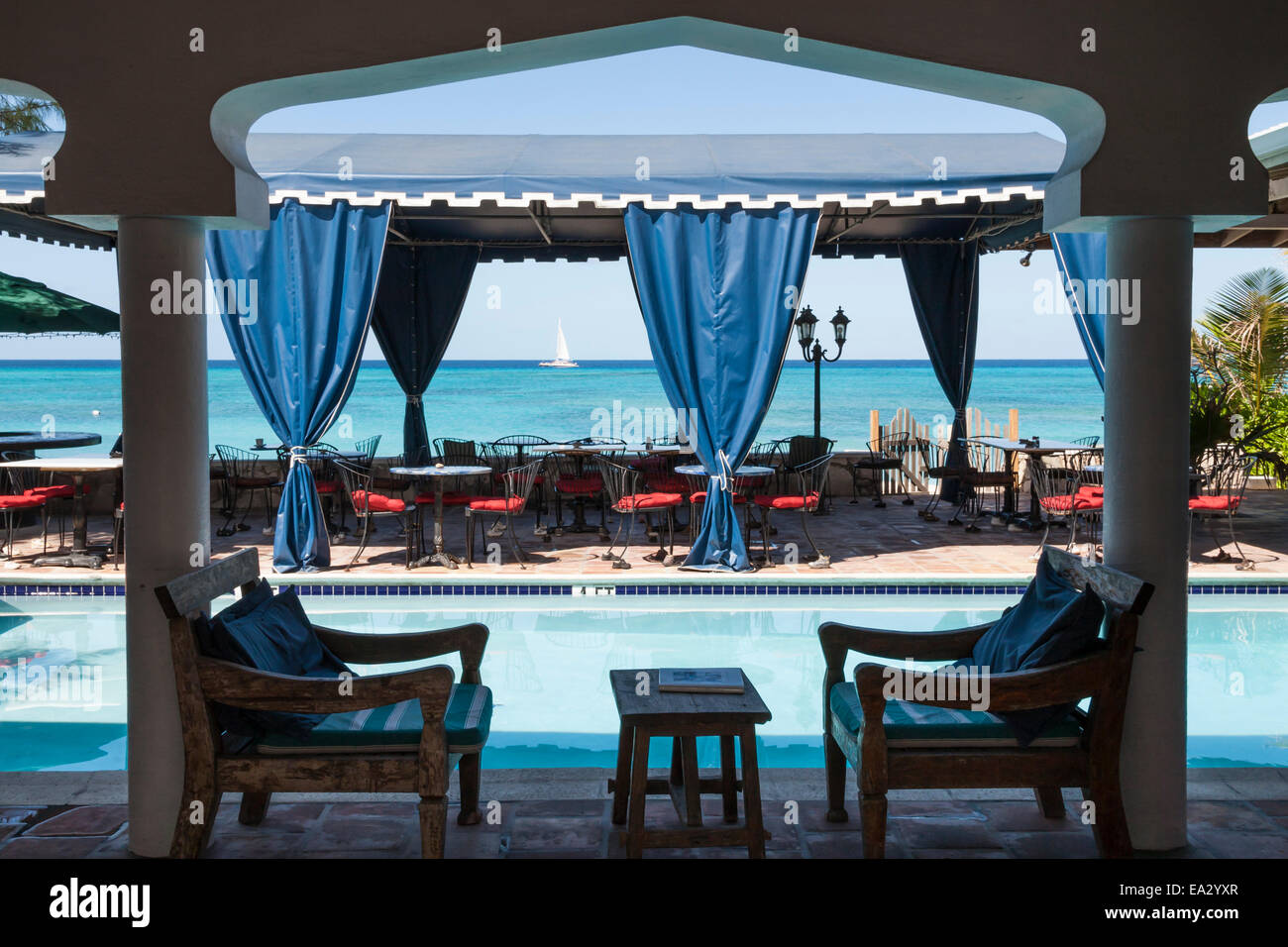 Hotelterrasse mit Pool und Blick auf das blaue Meer mit vorbeifahrenden Katamaran, Cockburn Town, Grand Turk, Turks- und Caicosinseln, West Indies Stockfoto