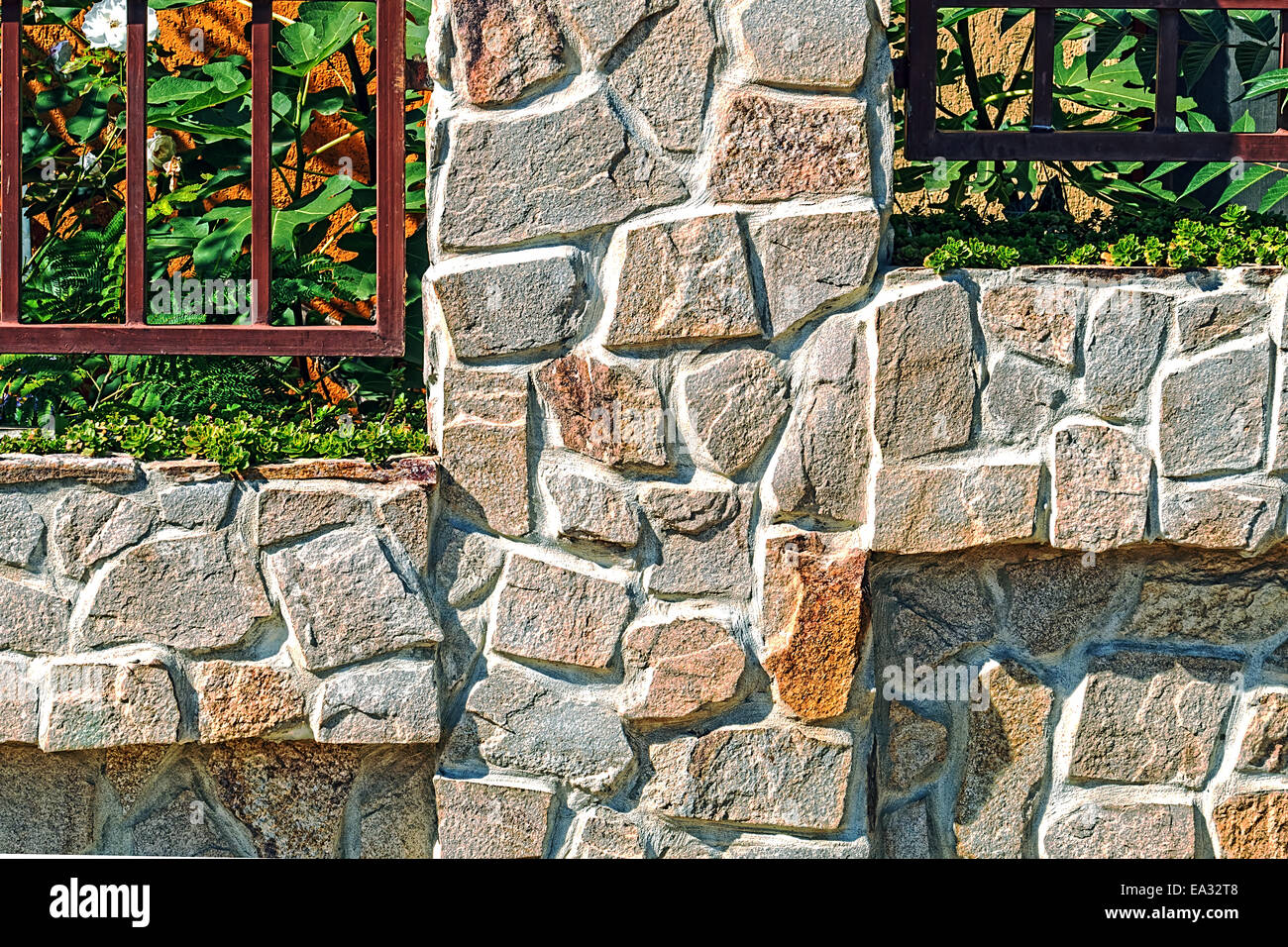 Zaun mit dekorativen Stein und Metall aus. Ziergrün. Stockfoto