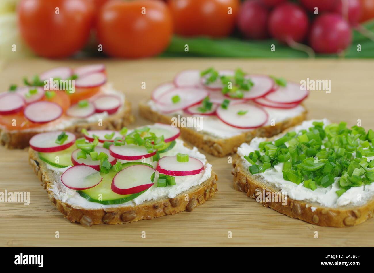 vier Scheiben Brot mit Quark und Gemüse Stockfoto