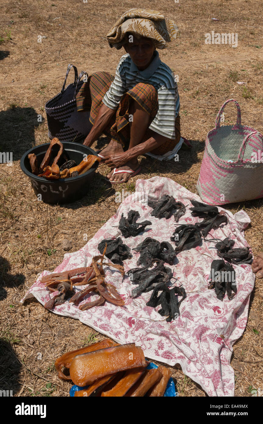 Ein Verkäufer auf einem Tauschmarkt, der darauf wartet, dass die Menschen Walfleisch mit Gemüse und Obst handeln. Lembata Island, Indonesien. Stockfoto