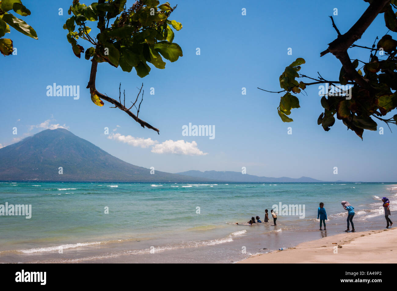 Menschen, die Freizeit an einem Strand mit Blick auf die Boleng-Straße und den Berg Boleng (Adonara-Insel) haben; fotografiert auf der Insel Lembata, Indonesien. Stockfoto