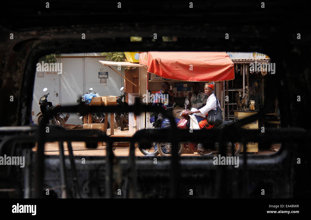 Ouagadougou, Burkina Faso. 6. November 2014. Eine Frau fährt vorbei an den Trümmern eines verbrannten Autos auf der Straße von Ouagadougou, der Hauptstadt von Burkina Faso, 6. November 2014. Führer der subregionalen Körper, Wirtschaftsgemeinschaft der westafrikanischen Staaten (ECOWAS) fordert die Militärbehörden und alle anderen Beteiligten arbeiten zur Errichtung einer Zivilisten geführte Übergangsregierung in Burkina Faso. © Liu Kai/Xinhua/Alamy Live-Nachrichten Stockfoto