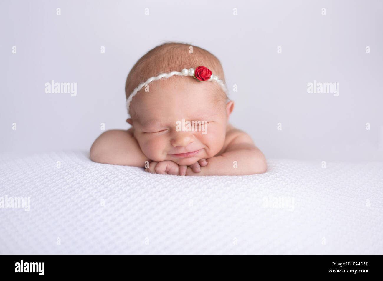 Portrait über sieben Tage alten neugeborenen Mädchen lächelnd. Sie trägt eine Perle und rote rose Stirnband und schläft auf weißem, text Stockfoto