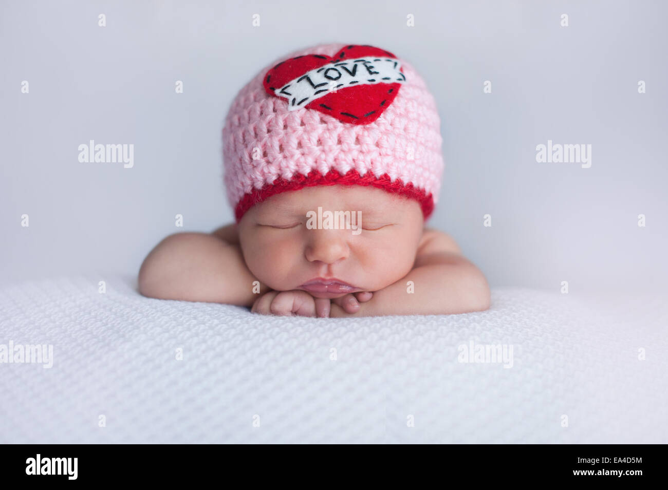 Porträt von einem sieben Tage alten schlafenden Baby Mädchen tragen eine gehäkelte Mütze 'Love'. Niedliche Schuss für den Valentinstag zu verwenden. Stockfoto