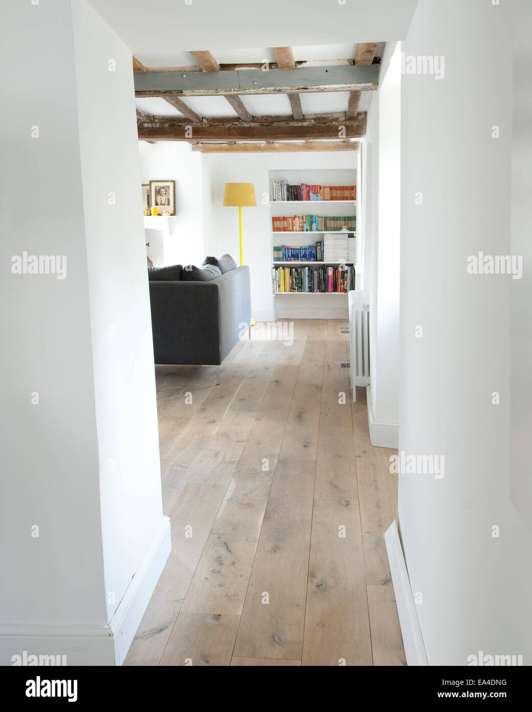 Blick durch den Flur, Wohnzimmer mit Bücherregal und grau Sofa im Landhaus Interieur, UK. Stockfoto