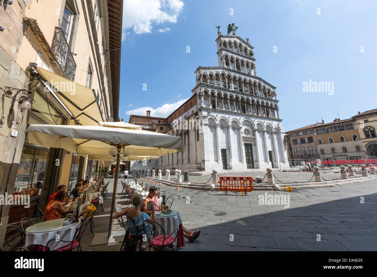 Touristen auf einer Terrasse auf der Piazza San Michele mit San Michele in Foro, Lucca, Toskana, Italien Stockfoto