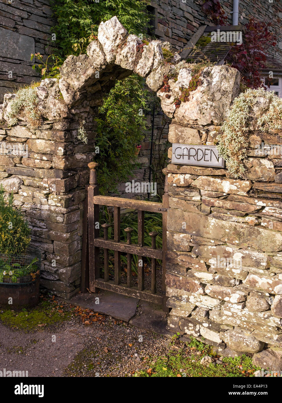 Alten Schiefer Stein Mauer mit Torbogen über Holztor in Garten Stockfoto