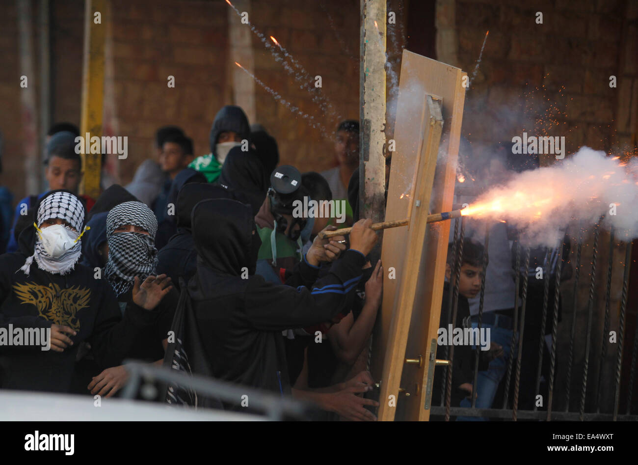 (141106)--JERUSALEM, 6. November 2014 (Xinhua)--maskierte palästinensische Jugendliche verwenden Türen als Schutzschilde bei Zusammenstößen mit israelischen Sicherheitskräften in die palästinensischen Flüchtlingslager Schuafat, Ost-Jerusalem, am 6. November 2014. Der israelische Ministerpräsident Benjamin Netanyahu am Donnerstag sicherte König Abdullah II von Jordanien, dass Israel nicht beabsichtigt, den Status quo in al-Aqsa-Moschee und die Verbindung in Ost-Jerusalem, Beamten und lokalen Medien sagte. Frische Zusammenstöße zwischen Steinwürfe Palästinenser und Polizei brach am Mittwoch, nachdem eine Gruppe von rechtsextremen Aktivisten versuchten, ein Gebet Vigi durchzuführen Stockfoto