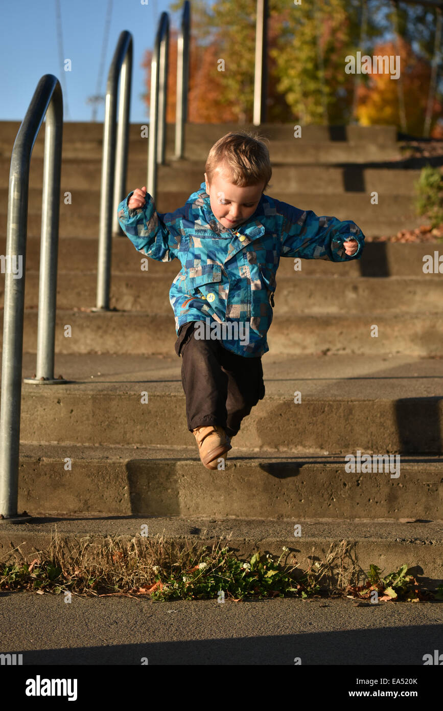 Ein kleiner Junge (2 1/2 Jahre alt) Stufen hinunter springen Stockfoto