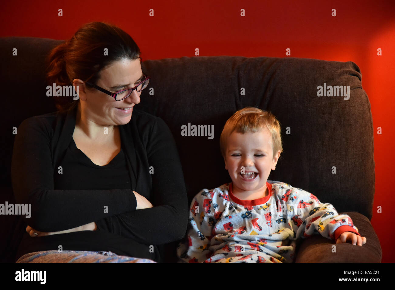 Mutter und Sohn im Pyjama, saß auf einem Sofa zusammen lachen Stockfoto