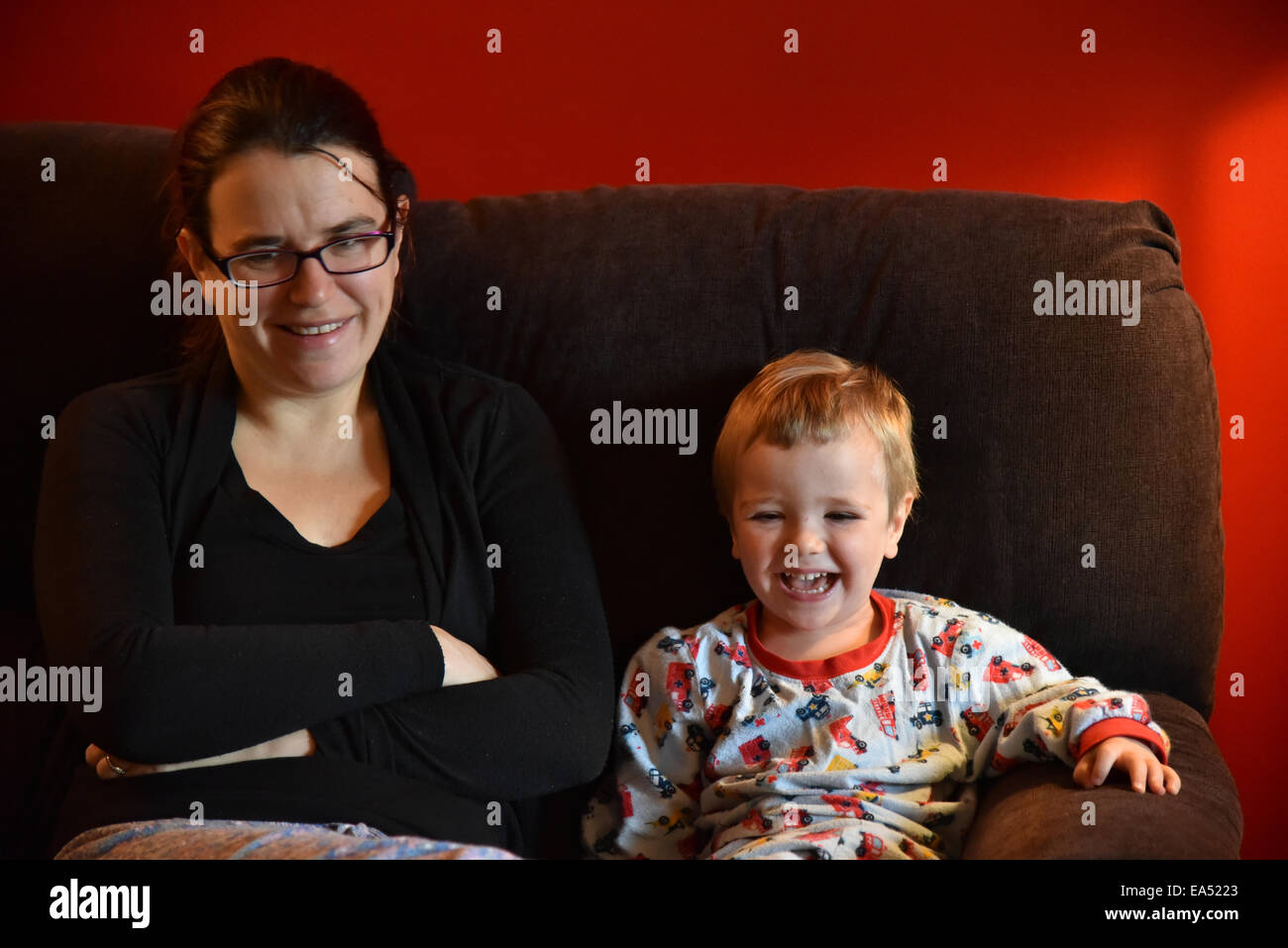Mutter und Sohn im Pyjama, saß auf einem Sofa zusammen lachen Stockfoto