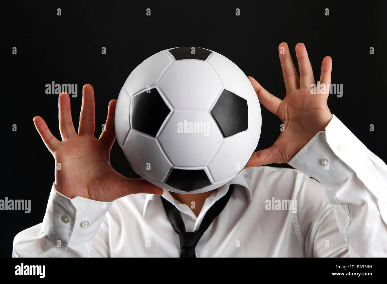 Attraktiver Mann mit weißem Hemd und Fußball vor schwarzem Hintergrund Stockfoto