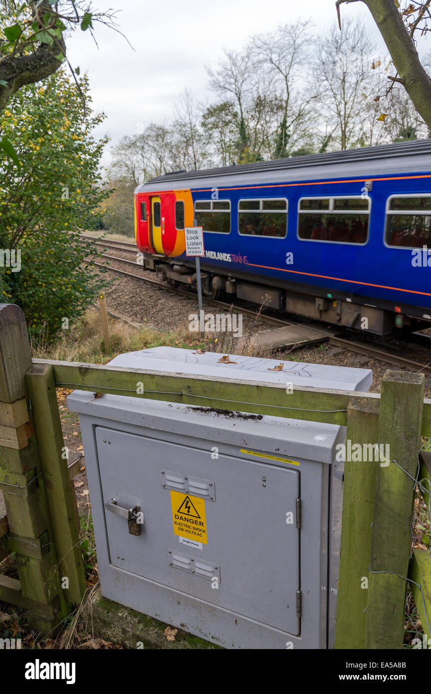East Midlands Zug überfahren einen öffentlichen Fußweg mit Warnschild und eine graue elektrische Abzweigdose. Stockfoto