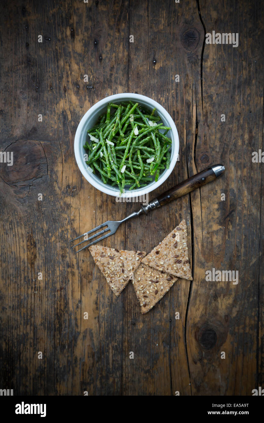Schüssel mit Mönchsbart Salat und Roggen Cracker auf dunklem Holz Stockfoto