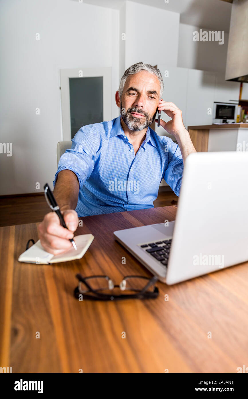 Porträt der Geschäftsmann mit seinem Smartphone telefonieren, während Sie Notizen machen Stockfoto