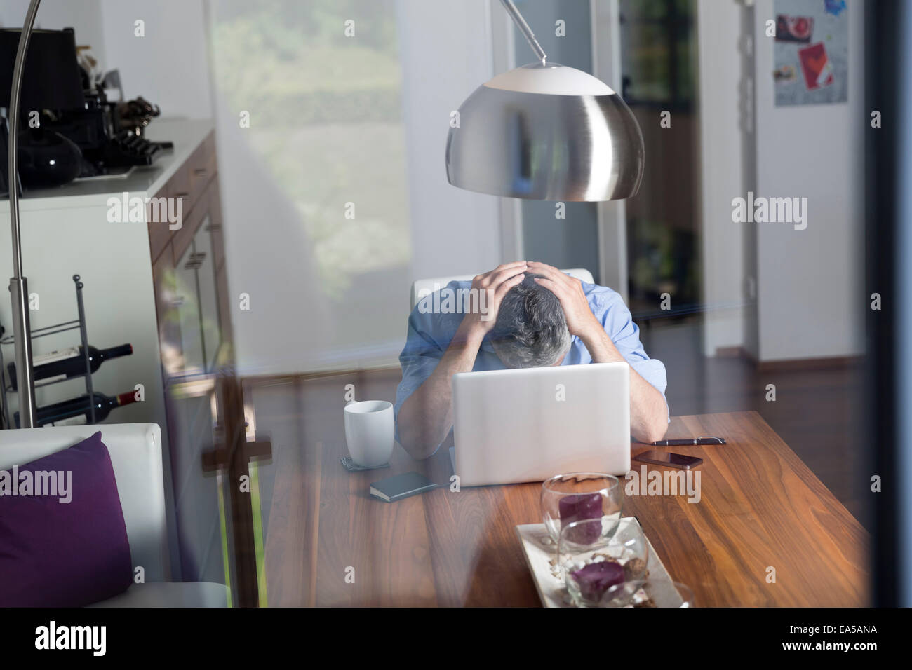 Überbeanspruchten Geschäftsmann mit Kopf in seinen Händen sitzt in seinem Büro zu Hause Stockfoto
