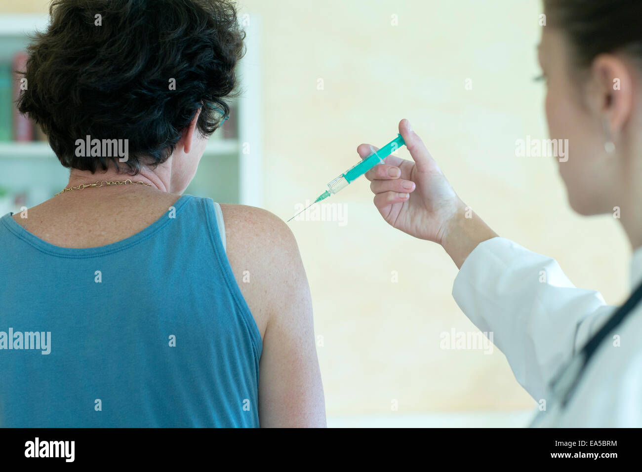 Junge Ärztin, die Injektion in den Oberarm des Patienten Stockfoto